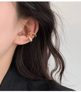 Detailed view of a triple-layer gold ear cuff with pearls and zircons worn on model ear