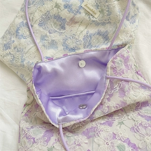 Close-up of floral lace shoulder bag with purple satin lining and magnetic metal buckle