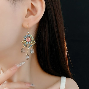 Detail of ethnic tassel earrings with blue flower motif and crystal water-drop pendants