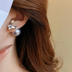 Détail de la boucle d'oreille papillon avec zircon argenté et perle bleu-gris sur modèle