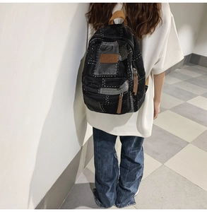 Detail of vintage patchwork denim backpack with white contrast stitching on model