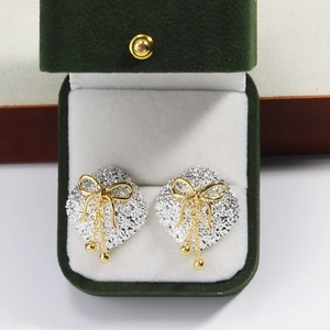 Close-up of geometric diamond earrings with gold bow and tassel in a green velvet box