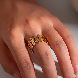 Macro detail of gold-plated open ring featuring intricate hollow patterns on a finger