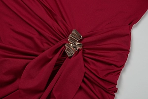Close-up of elegant red dress with gold metal hardware and gathered fabric detail