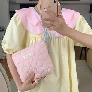 Pink quilted floral cosmetic bag with fluffy texture held in a mirror selfie scene