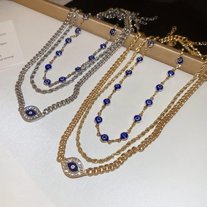 Detailed view of triple-layered necklaces with diamond-studded evil eye pendants