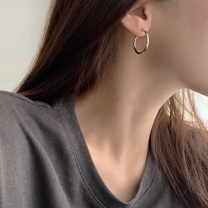 Close-up of polished silver hoop earrings on a model showing modern minimalist style