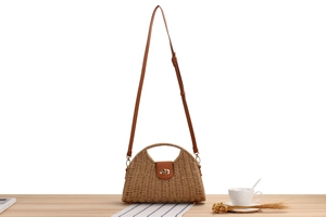 Detailed view of woven paper rope bag with leather strap on a decorative wooden table