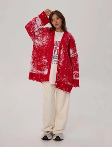 Detail of red Christmas knit cardigan with distressed hem and white snowflake texture pattern