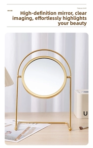 Detail of a rotating gold metal vanity mirror showing the sleek arch frame and base