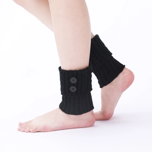 Detail of black cable knit leg warmers featuring stylish side buttons on soft texture