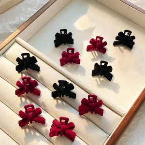 Detailed view of small velvet bow hair clips in red and black on a display tray