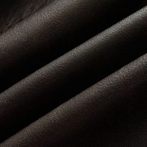 Macro shot of dark brown faux leather texture with natural grain and soft folds on a jacket