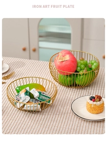 Detailed view of two gold iron fruit baskets with hollow mesh design on a beige tablecloth