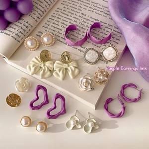 Elegant purple earring set with pearls and floral motifs on silk fabric and a book