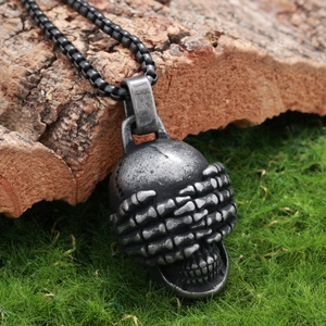 Gothic vintage stainless steel skull pendant with bone hands covering eyes on bark background