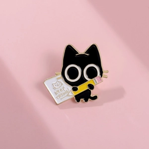 Detail of black cat enamel pin holding a yellow pencil with Keep Trying text
