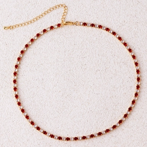 Detail van een gouden tennisketting met afwisselend rode en witte zirkonia-steentjes