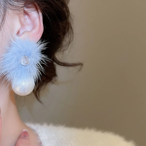 Detailed macro view of light blue plush pom-pom earrings with zircon and white pearl drops