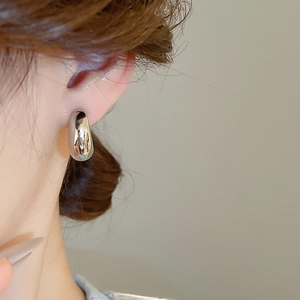 Dettaglio dell'orecchino a clip a goccia in argento lucido con curve metalliche minimali