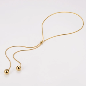 Detail of adjustable gold snake chain featuring a sliding buckle and two metal ball pendants