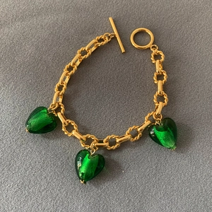Detailed shot of a gold-plated bracelet with three green heart glass pendants and OT clasp