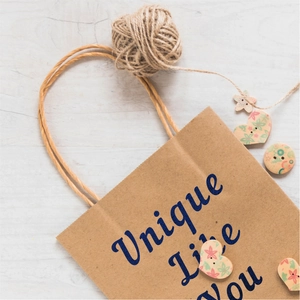 Close-up of brown kraft paper gift bag with blue Unique Like You text and twine handles