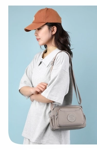 Detail view of khaki waterproof nylon crossbody bag with multi-layer zipper pockets