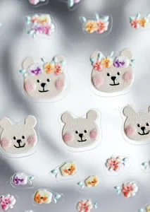 Macro detail of 3D embossed nail stickers featuring cute cartoon bears and floral patterns