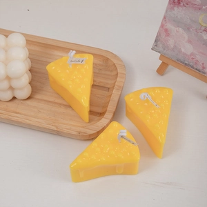Handmade cheese shaped scented candles in bright yellow color on a wooden tray