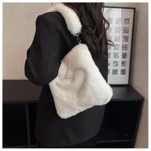 Dettaglio di una borsa di peluche bianca a forma di cuore indossata a tracolla da una modella