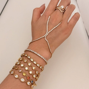 Detail of gold finger bracelet set with crystals and multilayer tennis bracelets