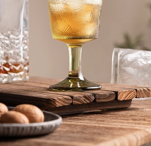 Detailed close-up of amber glass wine goblet with intricate embossed feather patterns