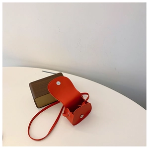 Detail of red mini crossbody bag for girls showing open flap and magnetic buckle