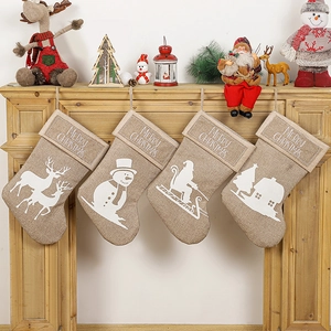 Set of 4 linen Christmas stockings with white festive silhouettes on a wooden mantel