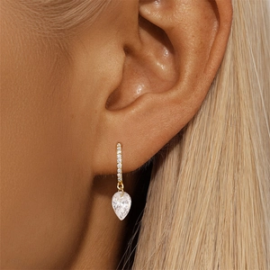 Macro shot of 18K gold S925 silver hoop earrings with a sparkling pear-cut zircon stone
