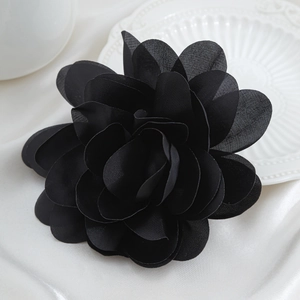 Close-up of handmade black fabric flower brooch with layered petals and silk texture