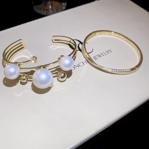 Detailed macro view of layered gold bracelets with pearls and sparkling pavé zircon stones