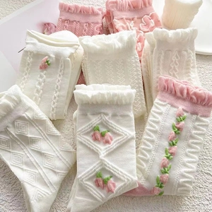 Details von Rüschenbündchen und 3D-Blumenstickerei auf rosa und weißen Baumwollsocken