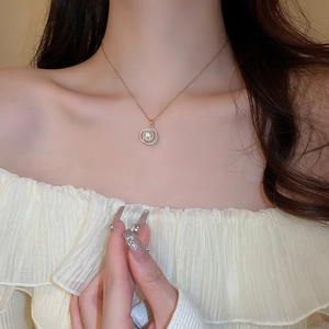Détail du collier doré avec cercle serti de zircons et pendentif perle sur mannequin
