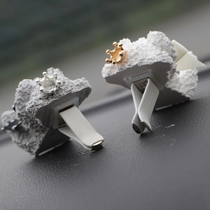 Detail of white resin teddy crown car air vent aroma clips with gold and silver accents