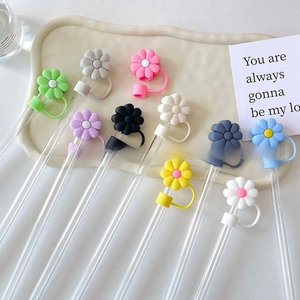 Daisy flower silicone straw covers in multiple colors on a white decorative tray