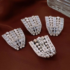 Detailed view of silver-toned fan-shaped rhinestone clips with rear fastener design