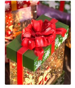 Close-up of a Christmas gift box water globe with a red ribbon and sparkling golden glitter