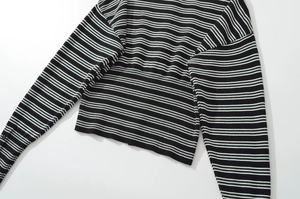Detailed close-up of a black and white striped knit sweater with ribbed cuffs and hem