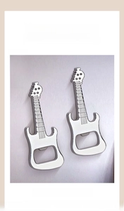 Détail de deux décapsuleurs guitare magnétiques fixés sur un réfrigérateur argenté
