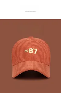 Detailed view of orange corduroy baseball cap with yellow NO 87 number embroidery