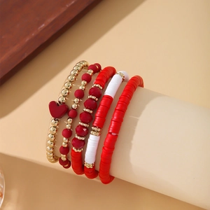 Detail of bohemian bracelet set with red heart pendant, gold beads and clay discs