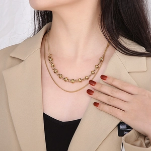 Double-layered gold stainless steel necklace with butterfly beads worn by a model