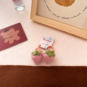 Detailed view of pink plaid fabric strawberry hair ties with green leaves on card